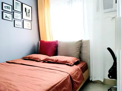 a bed with pink pillows in a room with a window at Green 2 Residences Scandi-Industrial Hotel Type Interior in Dasmariñas