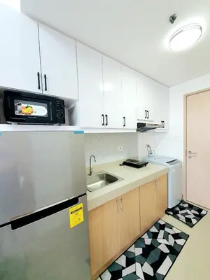 a kitchen with white cabinets and a sink and a microwave at Green 2 Residences Scandi-Industrial Hotel Type Interior in Dasmariñas