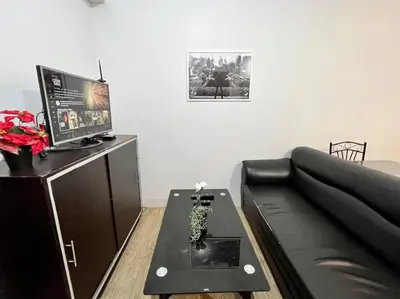 a living room with a black couch and a table at Sweet Home with WiFi and Netflix in Manila