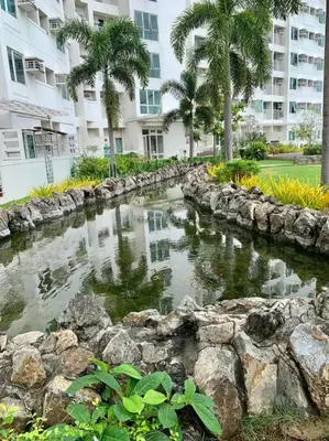 a pond in front of a building with palm trees at Sweet Home with WiFi and Netflix in Manila