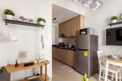 a kitchen with a stainless steel refrigerator and a table at Shore 2 Apartment with Balcony in Manila
