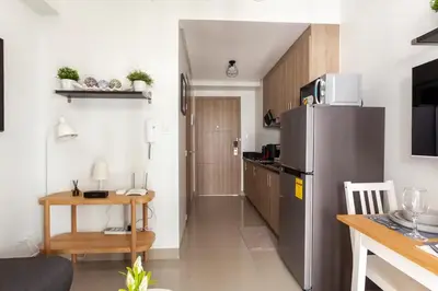 a small kitchen with a refrigerator and a table at Shore 2 Apartment with Balcony in Manila