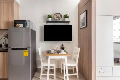 a small kitchen with a table and a refrigerator at Shore 2 Apartment with Balcony in Manila