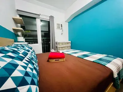 a blue bedroom with a bed with a suitcase on it at Cozy Place Anuva Residences in Manila