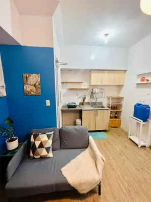 a living room with a couch and a kitchen at Cozy Place Anuva Residences in Manila