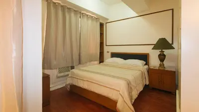 a bedroom with a bed and a window and a lamp at Sunette Tower Makati in Manila