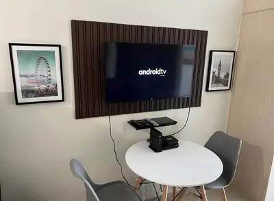 a room with a white table and a tv on a wall at JAZZ Residences - 1 Bedroom with Balcony - Cable, Wifi & Netflix in Manila