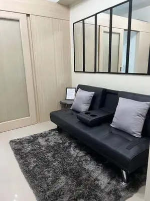 a black couch in a living room with a mirror at JAZZ Residences - 1 Bedroom with Balcony - Cable, Wifi & Netflix in Manila