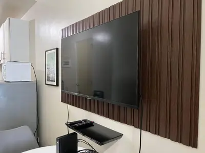 a large flat screen tv hanging on a wall at JAZZ Residences - 1 Bedroom with Balcony - Cable, Wifi & Netflix in Manila