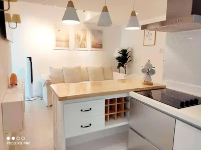 a kitchen with white cabinets and a wooden counter top at Azure SKYVIEW PENTHOUSE minimalist unit in Manila