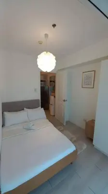 a bedroom with a large white bed and a light at Azure SKYVIEW PENTHOUSE minimalist unit in Manila