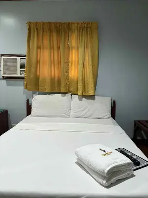 a bedroom with a white bed with a window at DUCK INN AND RESTAURANT in Manila
