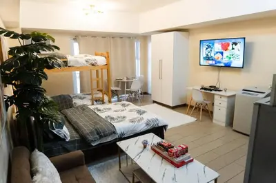 a living room with a couch and a bed in a room at A2J Luxury Venice Studio Suite Near BGC Malls in Manila
