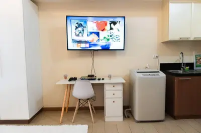 a kitchen with a desk and a tv on the wall at A2J Luxury Venice Studio Suite Near BGC Malls in Manila