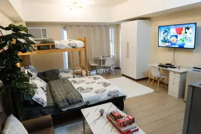 a living room with a bed and a desk in a room at A2J Luxury Venice Studio Suite Near BGC Malls in Manila