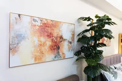 a painting hanging on a wall next to a plant at A2J Luxury Venice Studio Suite Near BGC Malls in Manila
