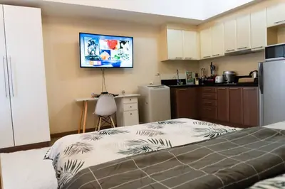 a kitchen with a bed and a tv on the wall at A2J Luxury Venice Studio Suite Near BGC Malls in Manila