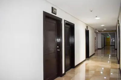 a hallway with three black doors and a tile floor at Birchtower by Jeizel Manila City in Manila