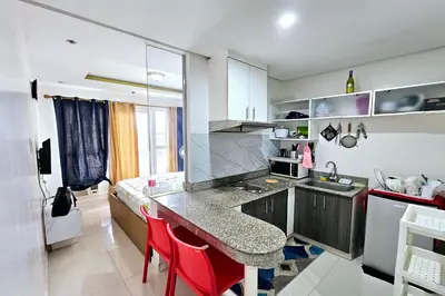 a kitchen with a counter and red chairs in it at Birchtower by Jeizel Manila City in Manila
