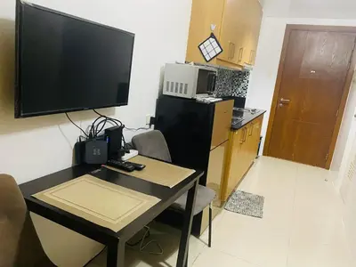 a living room with a table with a television and a kitchen at Shell Residences C15 Shortwalk Sm Mall Of Asia/Airport in Manila