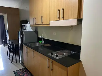 a kitchen with wooden cabinets and a sink and a refrigerator at Shell Residences C15 Shortwalk Sm Mall Of Asia/Airport in Manila