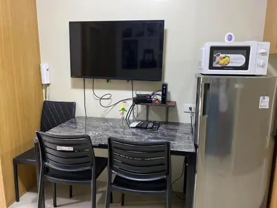 a room with a table with chairs and a television at Shell Residences C15 Shortwalk Sm Mall Of Asia/Airport in Manila