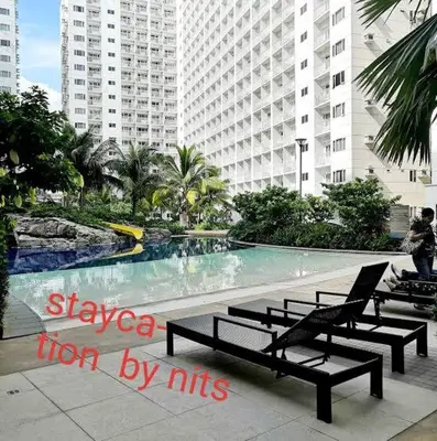 a swimming pool with benches in front of a building at Shore Residence D10 Near Mall Of Asia- Airport in Manila