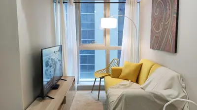 a living room with a yellow couch and a television at Uptown Parksuites BGC 2 bedroom 2 bath in Manila