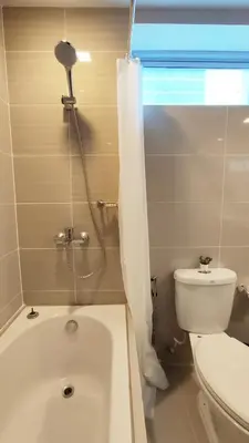 a bathroom with a tub and a toilet and a window at Uptown Parksuites BGC 2 bedroom 2 bath in Manila