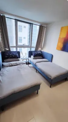two beds and a couch in a room with windows at Uptown Parksuites BGC 2 bedroom 2 bath in Manila