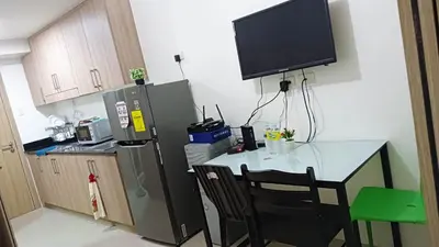 a kitchen with a table and a television on the wall at Shore Residence D11 Shortwalk Mall Of Asia/ In't Airport in Manila