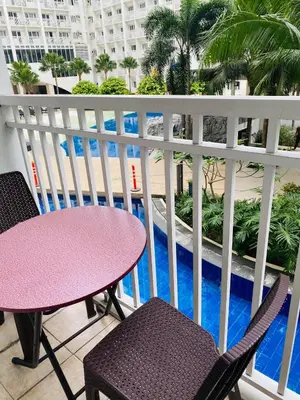 a balcony with a table and chairs and a pool at Shore Residence D12 Near Airport- SM Mall Of Asia in Manila