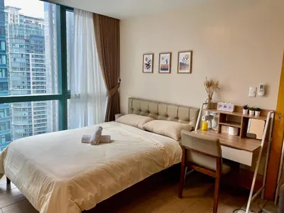 a bedroom with a bed and a desk and a window at One Uptown Residence BGC in Manila