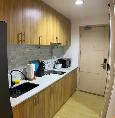 a kitchen with wooden cabinets and a sink and a microwave at SEA Residences in Pasay near Mall of Asia in Manila