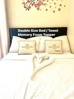 a bed with two pillows and a sign on the wall at Borbon's Condo Suite in Manila