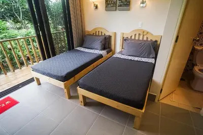 two beds in a room with a balcony at Tagaytay Foothills Cherimoya Farm Staycation in Biboyan