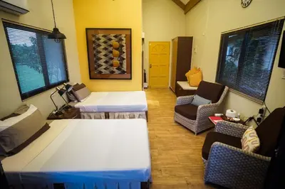a room with two beds and a couch and chairs at Tagaytay Foothills Cherimoya Farm Staycation in Biboyan