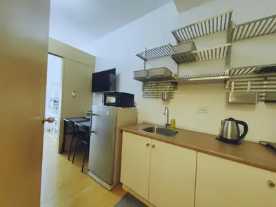 a kitchen with a sink and a refrigerator and shelves at Crib's nr.BGC in Manila