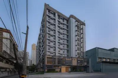 a tall white building on a city street at The Grid Co-Living Managed by HII in Manila