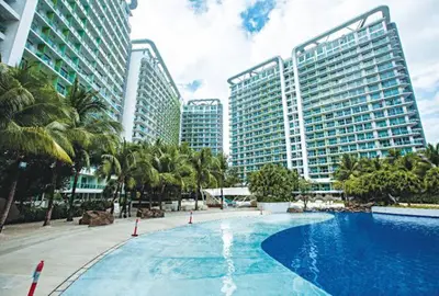 a large swimming pool with palm trees and tall buildings at Azure Residence A8 Near Sm Mall/Airport +free wifi in Manila