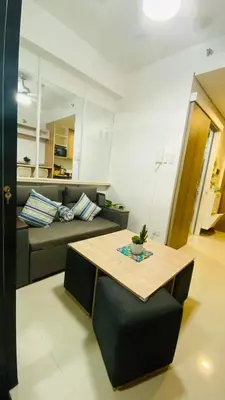 a living room with a couch and a table at Cozy 1Br with Netflix & Balcony Pool View Condo in Manila