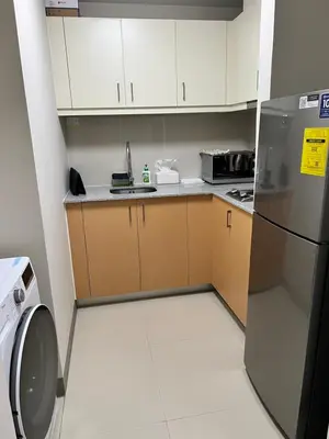 a small kitchen with white cabinets and a refrigerator at Uptown Parksuites II in Manila
