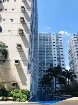 a tall building with a swimming pool in front of it at Shore Residence Staycation unit at Mall of Asia in Manila