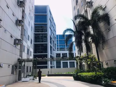 a man walking in front of a tall building at Shore Residence Staycation unit at Mall of Asia in Manila