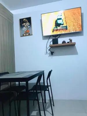 a table with chairs and a television on a wall at Condo- tel for At Mall of Asia Philippines in Manila
