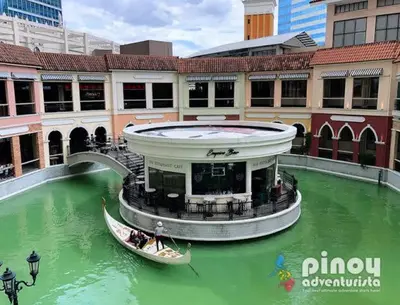 a boat in a green river in a city at Morgan Suite BGC Shortwalk3 Venice Mall free pool gym in Manila