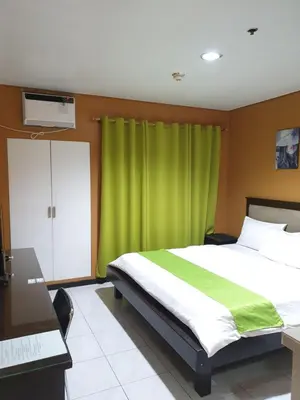 a bedroom with a bed with a green curtain at Sab R. Bel air soho in Manila