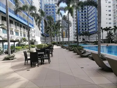 a patio with tables and chairs next to a pool at The FINEST Sea Residences Condo in Manila