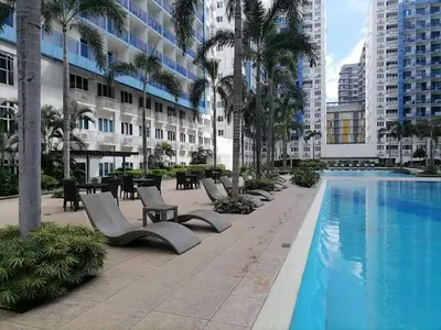 a hotel swimming pool with chairs and tables and buildings at The FINEST Sea Residences Condo in Manila