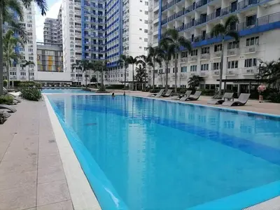 a large swimming pool with chairs and buildings at The FINEST Sea Residences Condo in Manila